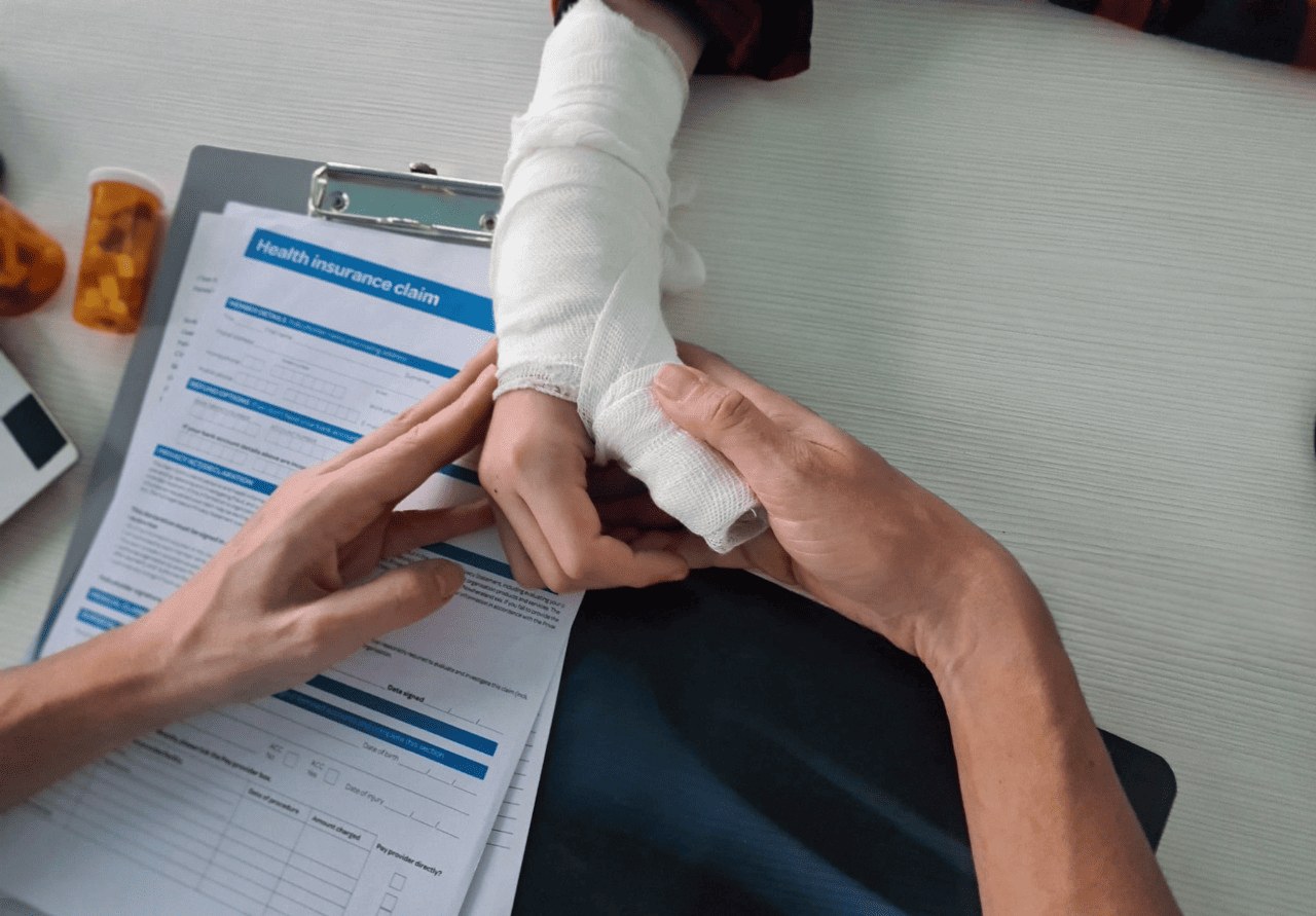 A WorkCover doctor helps a patient fill out a health insurance claim form for an injured hand.